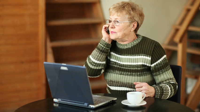 Senior woman with laptop talking on mobile phone