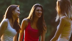 Three friends, young girls, having fun in park, talking, laughing, medium shot.
