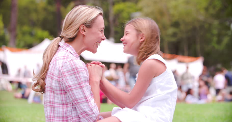 Mother and daughter Eskimo kissing at an outdoor event