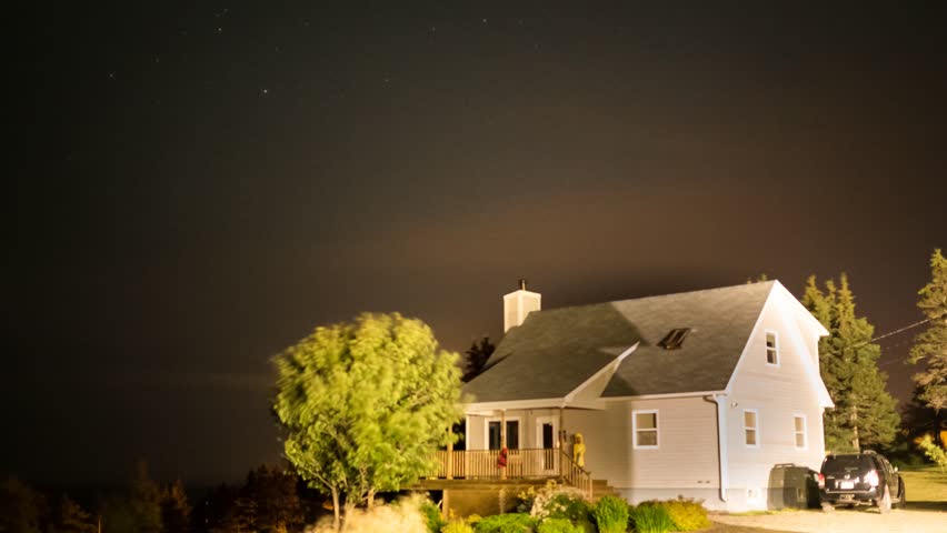 A time-lapse of stars rotating above a house at night