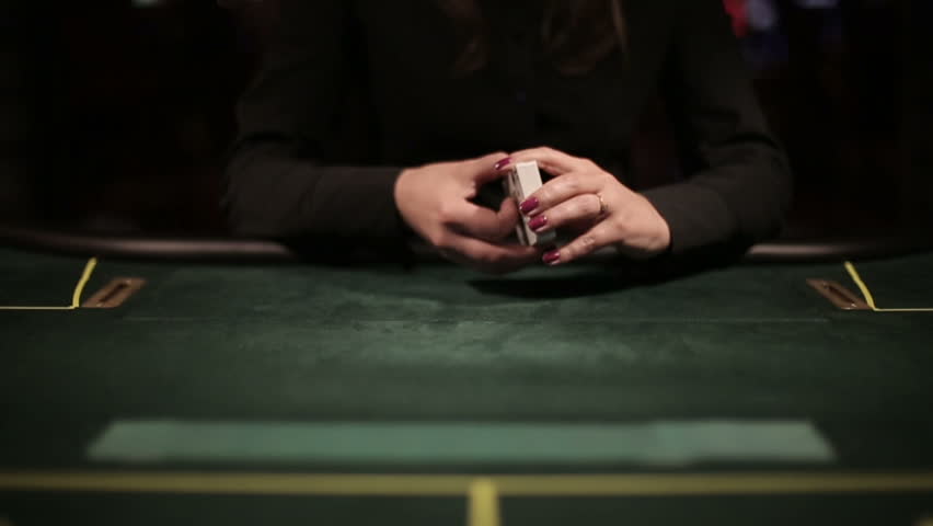 Poker dealer shuffling playing cards fanning out the deck on the table. Slow motion