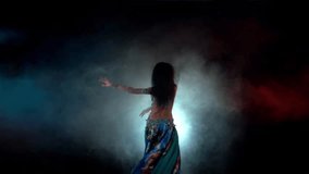 Movement of torso of beautiful woman finishing dancing belly dance in blue dress with long dark hair , back light, slow motion, in smoke, on black, red, blue background, brunette - Powered by Shutterstock - Get 15% off with code: PIKWIZARD15