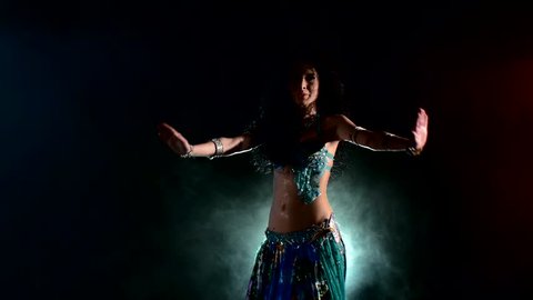 Sexy, young woman belly dancer arabian in exotic dress dancing exotic dance, on red, blue, smoke, back light