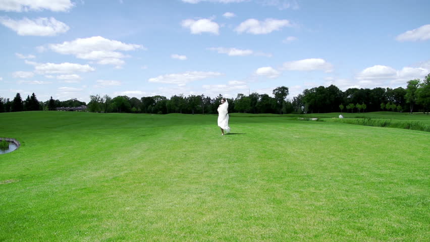 Very attractive women / girl in wedding dress walking / running  around green field / golf. Lake and wind. Slow motion. wedding video