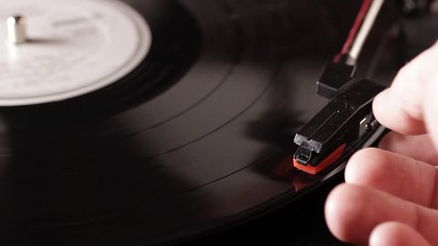 Close up macro of a record being played on a retro turntable that plays vinyl vintage records. Record players and turntables were popular in the 50s, 60s, and 70s and are now used by DJs.