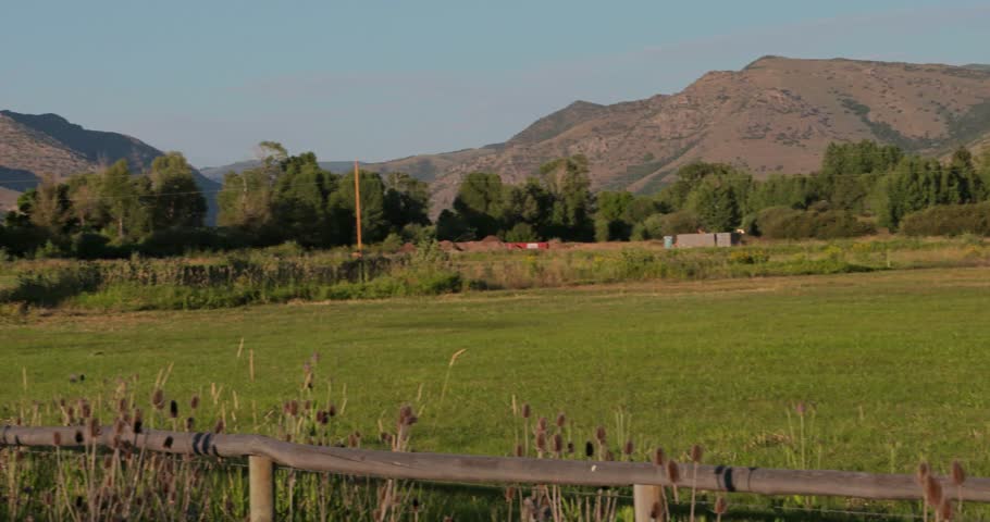 A barn sits in a peaceful mountain valley at sunset.