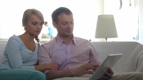 A husband and wife sitting together, the man working with a laptop