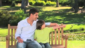 Father with his son sitting on a bench while looking at something