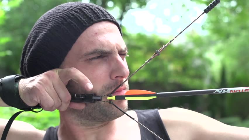 Young man shooting archery, close-up, slow motion.