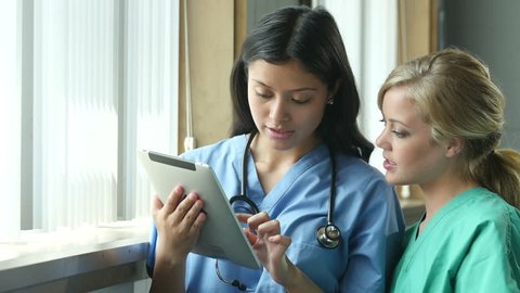 Two nurses consulting and looking at information on an ipad/tablet, close up shot