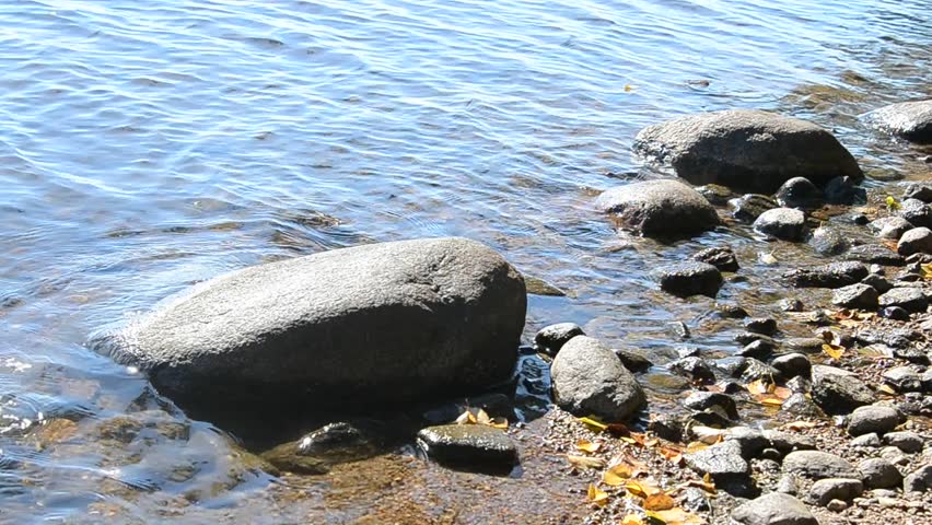 Shores of a lake with rock at sunny summer day.