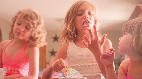 A little girl tries to pull a lollipop out of her sister's mouth and her fingers get sticky