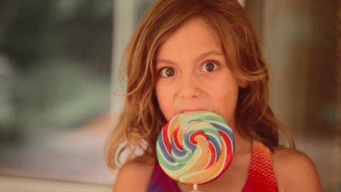 A young girl eating a lollipop
