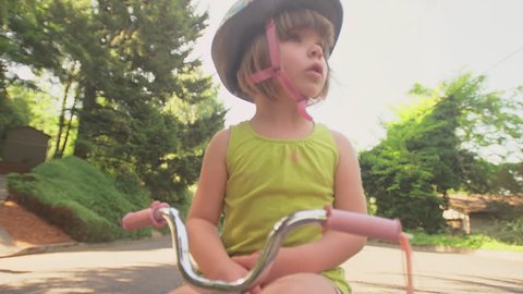 An upset little girl crosses her arms and gets off her bike