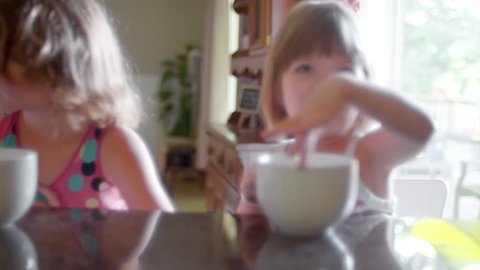 Three sisters sitting at a kitchen counter with large mugs and waiting for breakfast