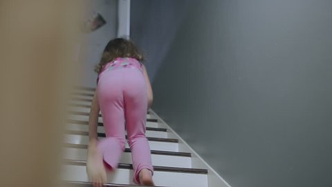 A girl runs up a set of stairs and a dog runs up after her