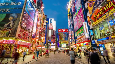 TOKYO, JAPAN - AUGUST 1, 2015: Crowds pass below colorful signs in Akihabara. The historic electronics district has evolved into a shopping area for video games, anime, manga, and computer goods.
