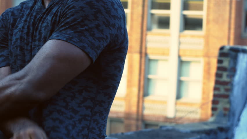 Very fit black male athlete taking off his shirt in the middle of workout