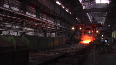 DONESK/UKRAINE - JAN 19 2012: Four Workers at the Machine Metal Rolling Metal Long Sheet of Metal Orange Hot Metal Sheet on a Rollers Workers Men in Safety Helmets, Donetsk Metallurgical Plant, pouring of liquid metal from ore,
