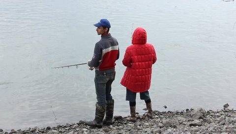 young couple fishing together by a river