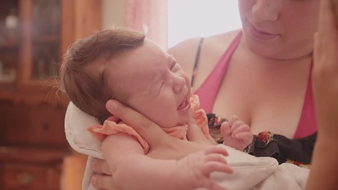 A mother tries to calm her crying newborn baby