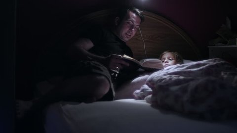 A father reading his daugher a book before bed