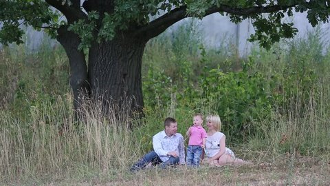 family sitting in the grass under a tree