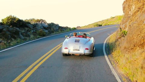 Happy Couple Driving on Country Road into the Sunset in Classic Vintage Sports Car. Cabriolet Steadicam Shot.