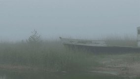 An old abandoned boat on the fod in the small port in a town in a foggy area