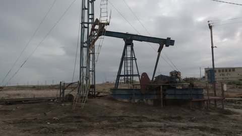 Oil lake. Oil and gas industry. Work of old oil pump jack on a oil field. No color correction