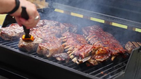 A man barbecues ribs and steaks for a summer party