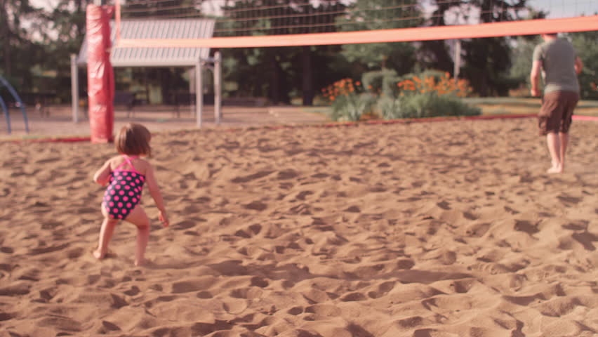 A little girl lays down in the middle of a volleyball game with her dad