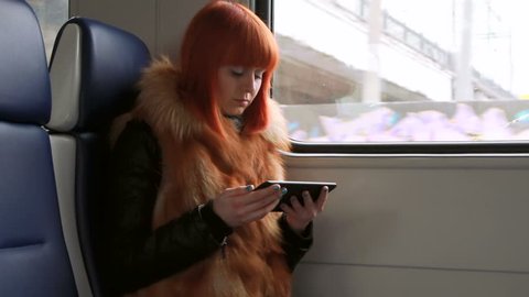 Redhead girl reads an sms in the train