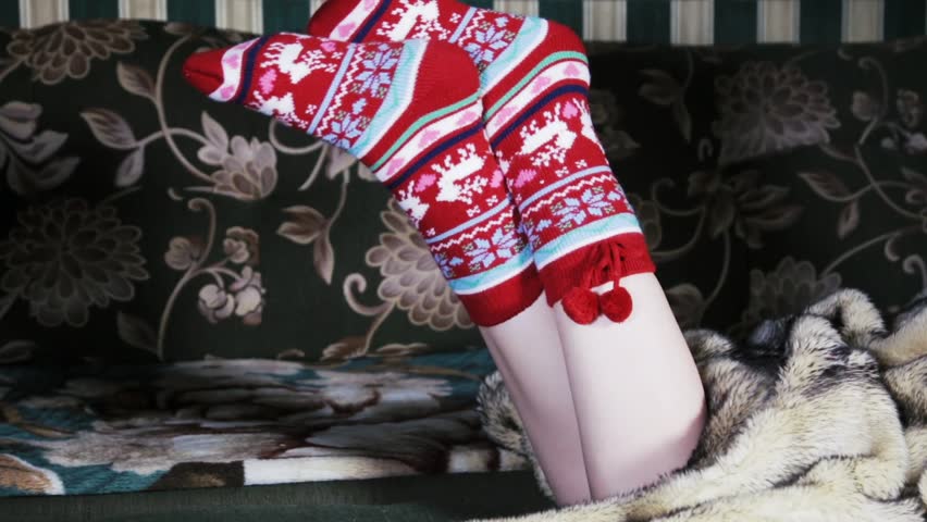 Female legs in Christmas socks under a blanket of fur