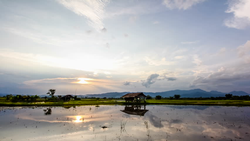 Time lapse moving clouds at sunset over fields