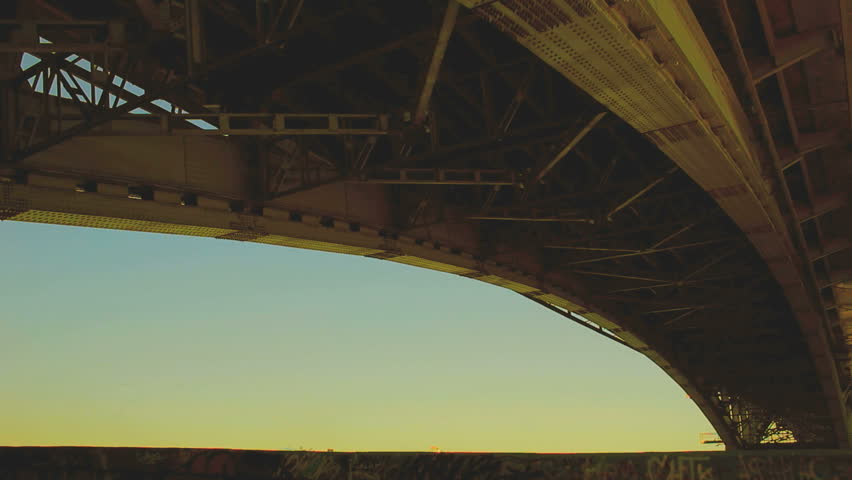 Silhouette of young man running under bridge summer evening