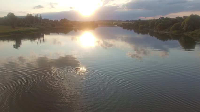 Swimmer on lake at sunset.