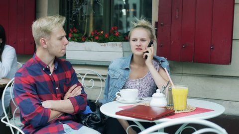 Couple talking on cellphone in the cafe and receiving bad news
