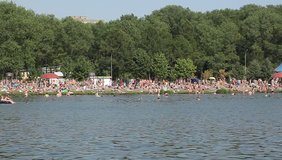 Video crowds of tourists on the shore of the pond in the hot summer