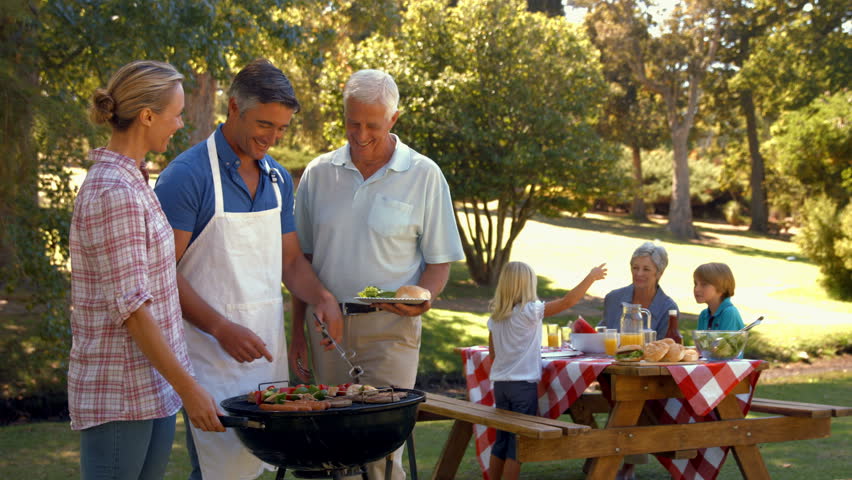 Happy man doing barbecue for his family in a sunny day