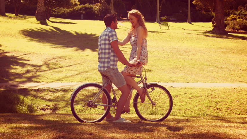 Cute couple on a bike ride in the park on a sunny day
