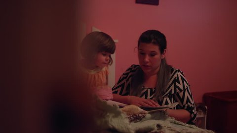 A mother reads her daughter a book before bed