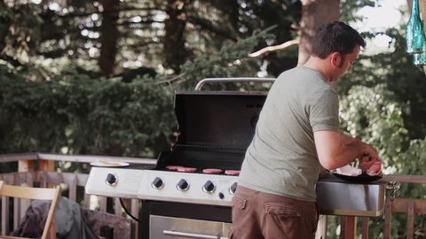 A man putting hamburger patties on a barbecue