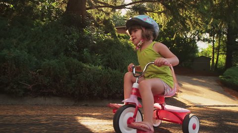 An adorable little girl happily riding her tricycle