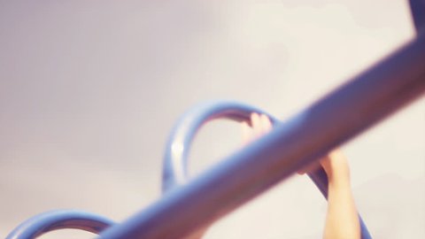 A young girl climbing on monkey bars, close up