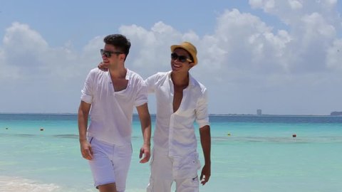 Couple of male friends walking at the beach