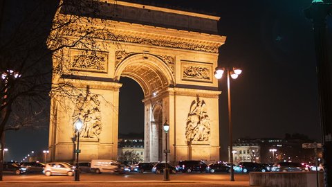 A view of the Arch of Triumph (Arc de Triomphe) by night, with cars and buses passing by. 