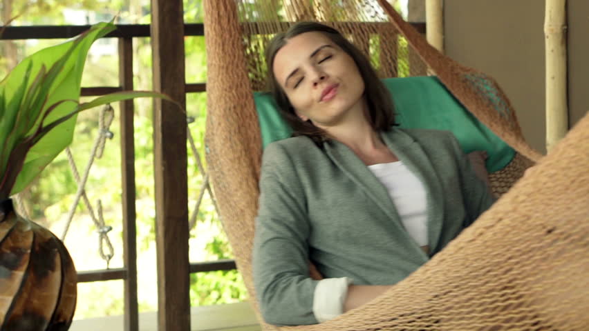 Young, pretty businesswoman sleeping on hammock on terrace 
