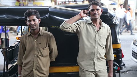 MUMBAI, INDIA - 8 JANUARY 2015: Indian men standing in front of a rickshaw on the street of Mumbai.