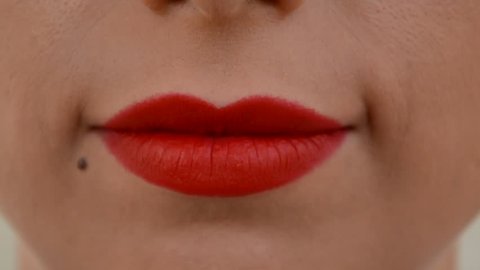 woman with birthmark blowing kiss with red matte lipstick